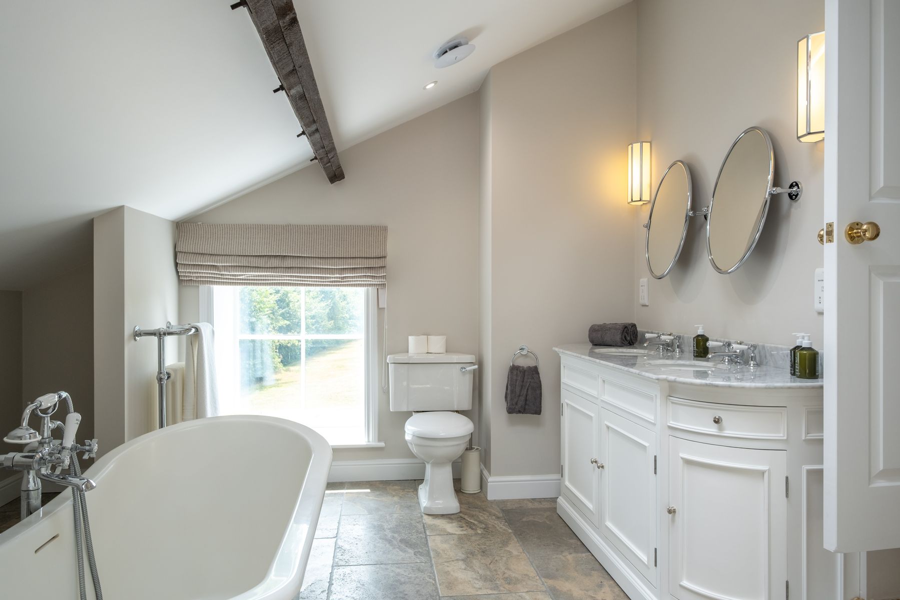 The principal bathroom, with roll-top bath, twin marble basins and an exposed beam