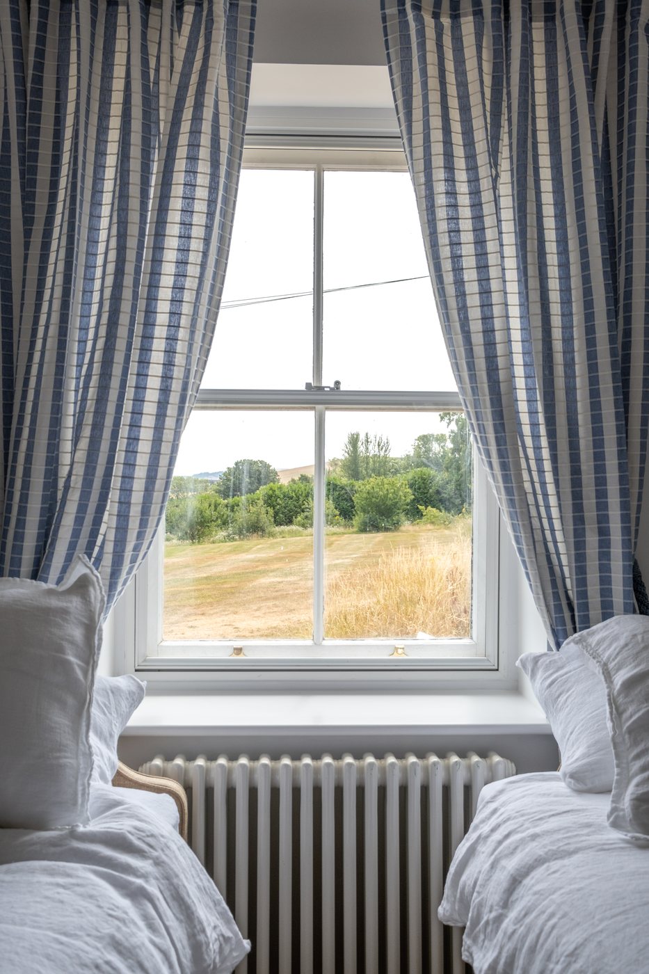 Twin beds framing a window with views across the estate