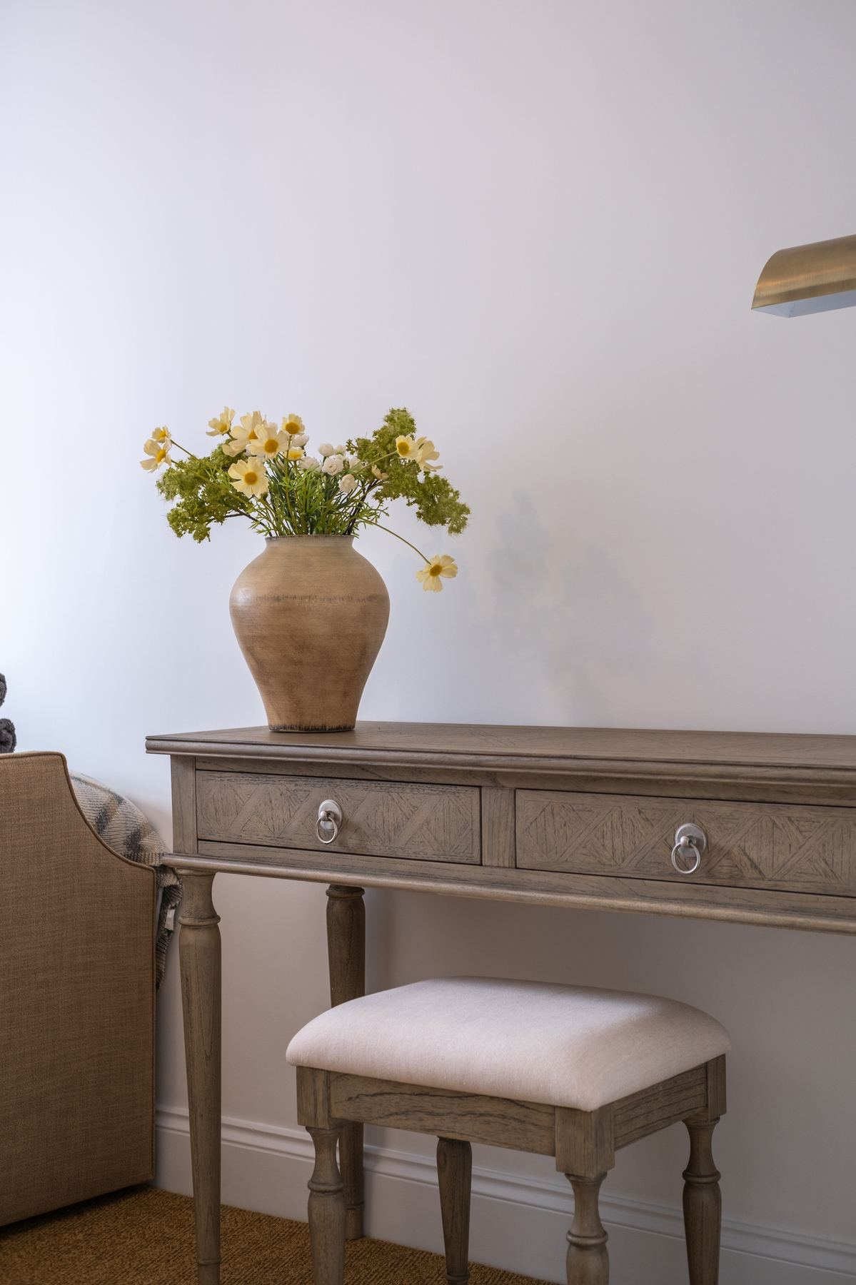 A dressing table with a stool and a vase of flowers