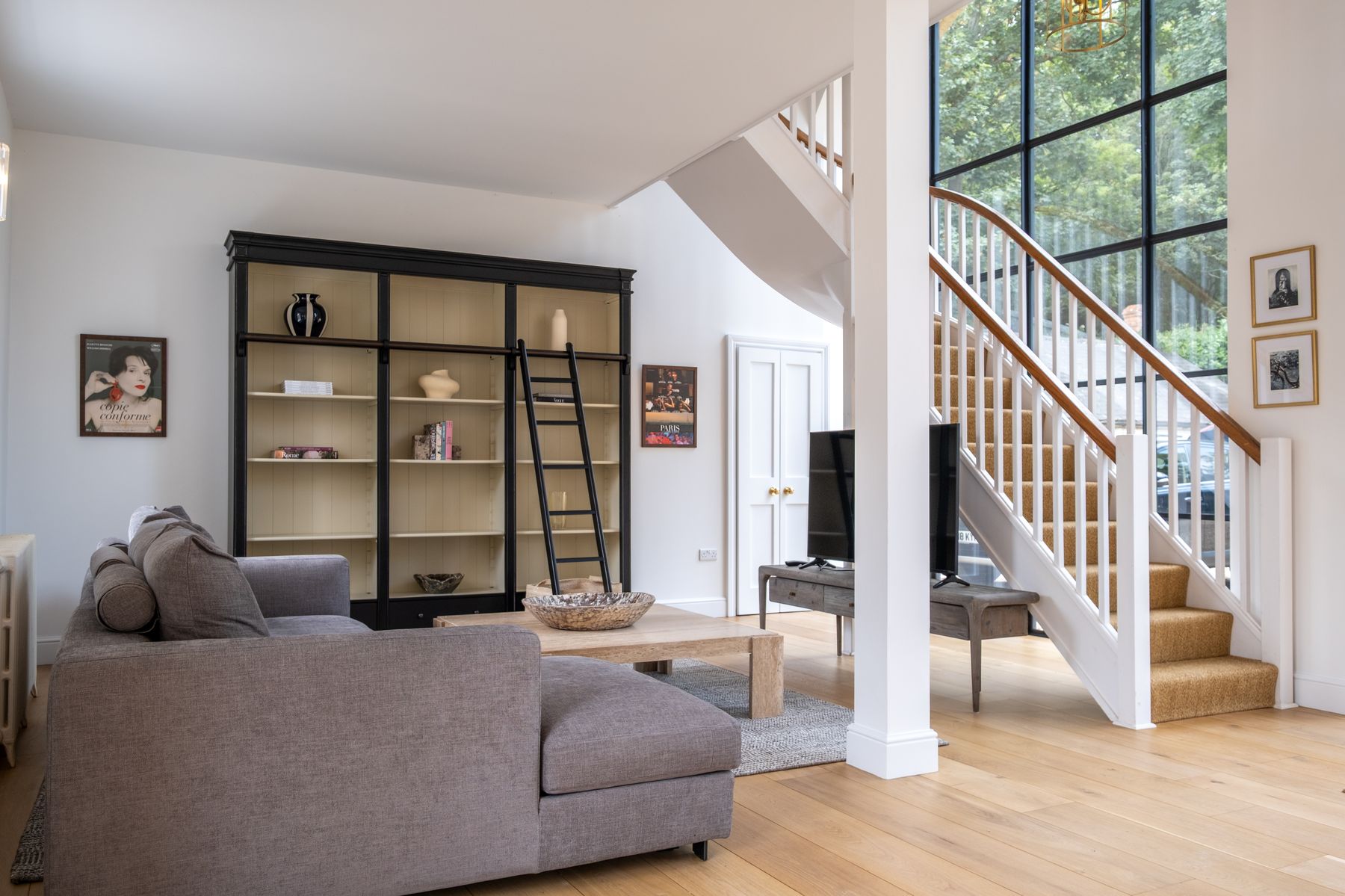 The living room and staircase, lit by the tall arched window