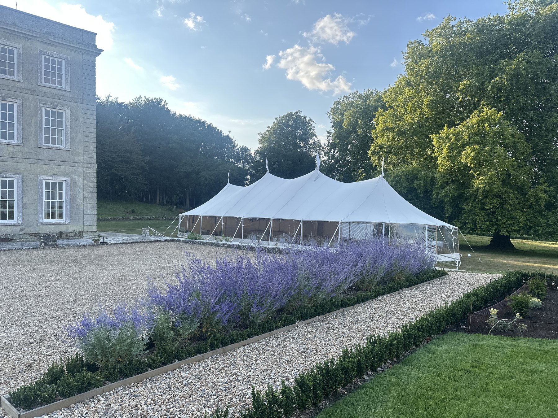 A marquee on the lawn beyond a border of lavender and the gravel walk