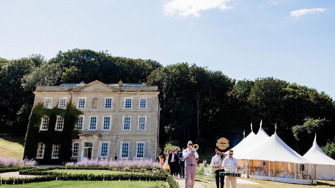 Guests and a band on the lawn beside the marquee, with the house behind