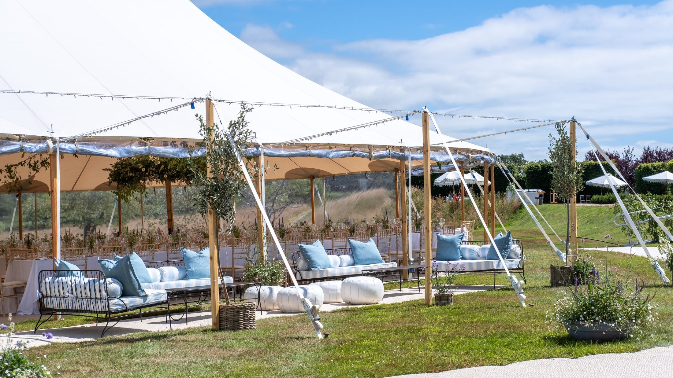 A sailcloth marquee in the parkland, with day beds and cushions beneath the canopy