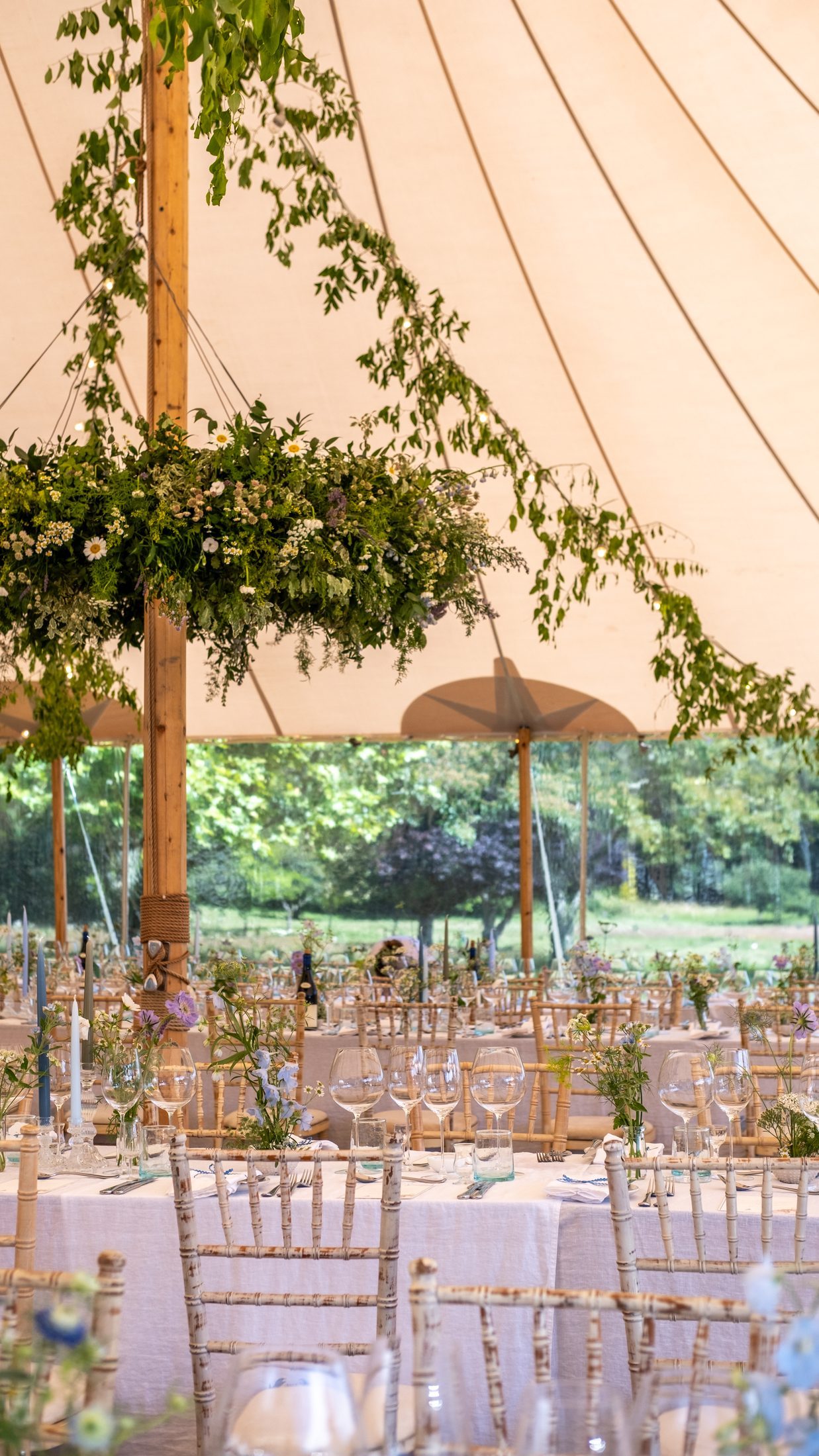 Garlands of greenery hanging above long tables inside the marquee