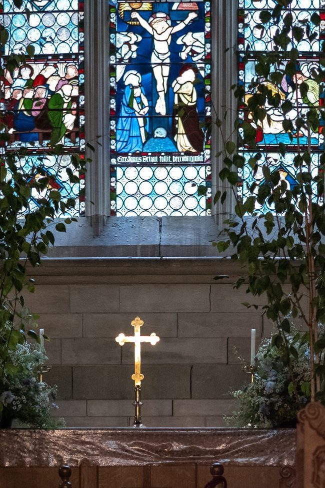 The chancel window of St Olave's, with the altar cross lit below it